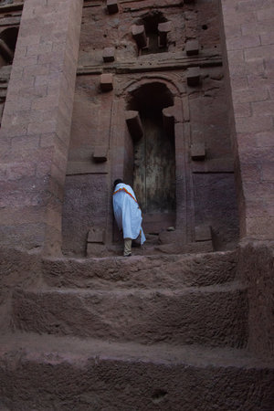 Lalibela, Ethiopia - Nov 2018: Man dressed up in white traditional ethiopian clothes praying at the rock excavated church in Lalibela.のeditorial素材