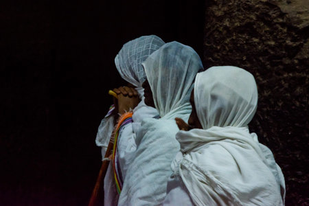 Lalibela, Ethiopia - Nov 2018: People dressed up in white traditional ethiopian clothes praying in interior of the the rock excavated church in Lalibela.のeditorial素材