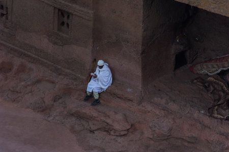 Lalibela, Ethiopia - Nov 2018: People dressed up in white traditional ethiopian clothes praying next to church excavated in rock in Lalibela.のeditorial素材