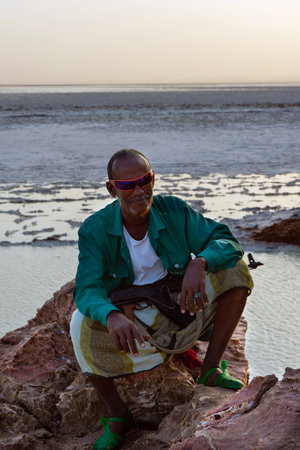 Dallol, Ethiopia - Nov 2018: Local scout man posing with rifle with the salt lake in Danakil desert in backgroundのeditorial素材