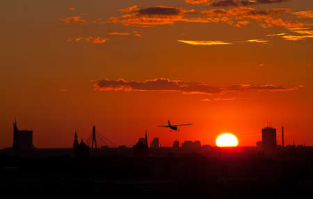 Sunset over the city with airplane の写真素材