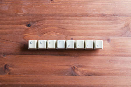 Sale word 2018 concept. Flat lay view from above on the table with computer keyboard keys buttons on a wooden background.の写真素材
