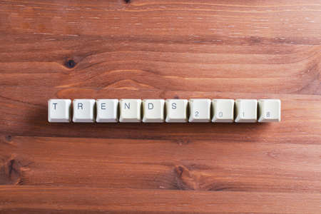 Trends 2018. Flat lay view from above on the table with computer keyboard keys buttons on a wooden background. New Year concept.の写真素材