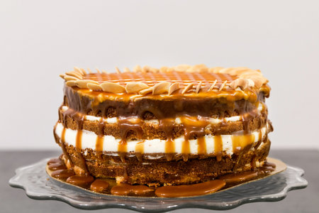 Sweet cake with sliced mindal nuts on a glass stand on a gray backgroundの写真素材