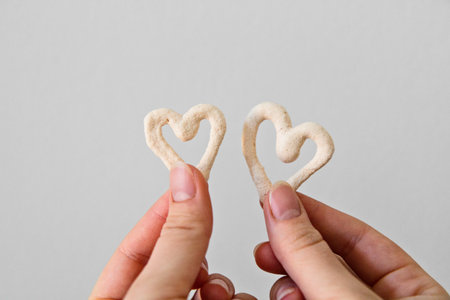 Two heart shaped meringue cookies in hand