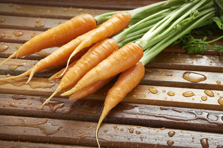 bunch of fresh carrots on wooden slatted backgroundの写真素材