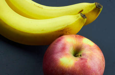 Still life of fresh fruits. Top view of red apple and bananas on dark background.の写真素材