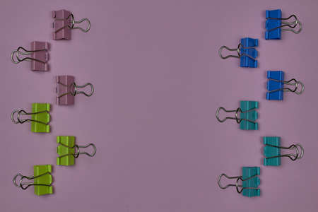 Pink, yellow, blue and green paper clips on a pink background with copy space for text.の写真素材