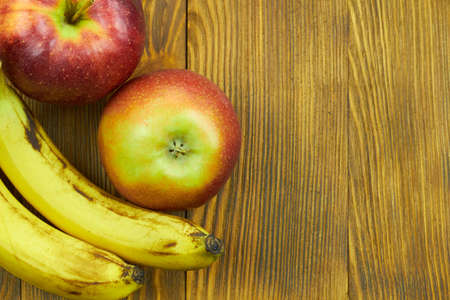 Fresh fruits. Close up view of red apples and bananas on wooden background with copy space for text.の写真素材