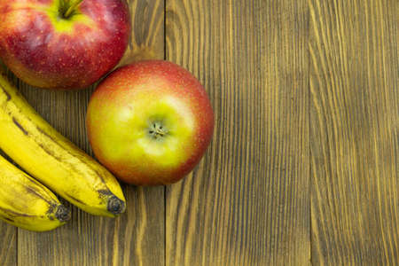 Fresh fruits. Close up view of red apples and bananas on wooden background with copy space for text.の写真素材