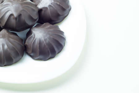Chocolate dipped marshmallows on white plate. Close up view, white background.の写真素材