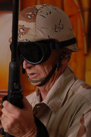Camouflaged old soldier with sniper rifle inside building