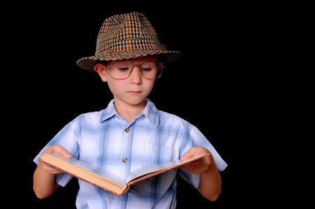 Young boy student carrying many books isolated on blackの写真素材