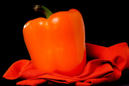 An orange bell pepper isolated over black