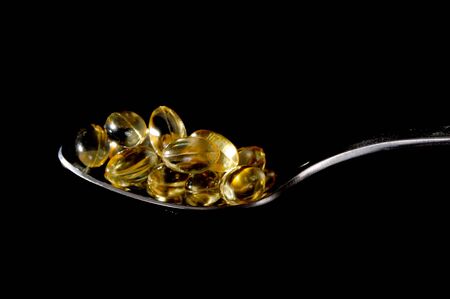 A spoon full of vitamin E isolated on blackの写真素材