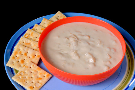 A steaming bowl of clam chowder with crackers isolated over blackの写真素材