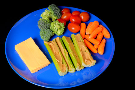 Healthy snack plate of celery, carrots, cheese, sprouts and tomatosの写真素材