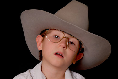 Young boy wearing a cowboy hat isolated on blackの写真素材