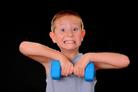 Young boy exercising with weights isolated on blackの写真素材