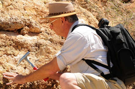 Senior geologist tap a rock formation with a hammerの写真素材