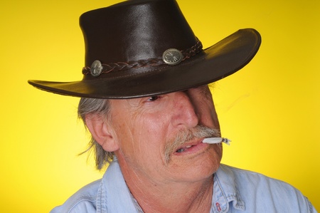 Old senior cowboy smoking a hand rolled cigaretteの写真素材
