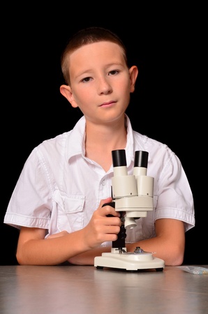 Young boy with a microscope isolated over blackの写真素材