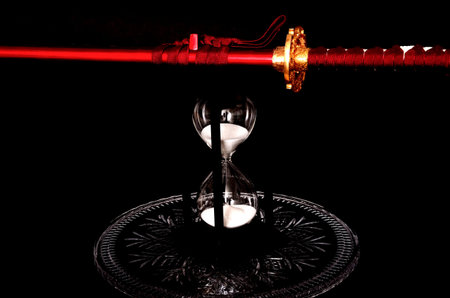 Sword and hour glass isolated over black