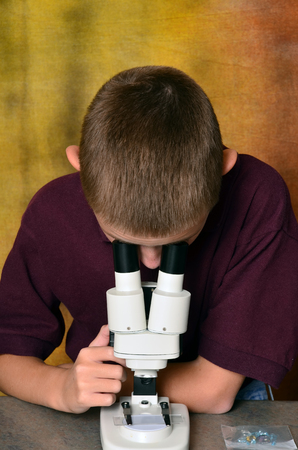Young boy scientist with microscope examining a sampleの写真素材