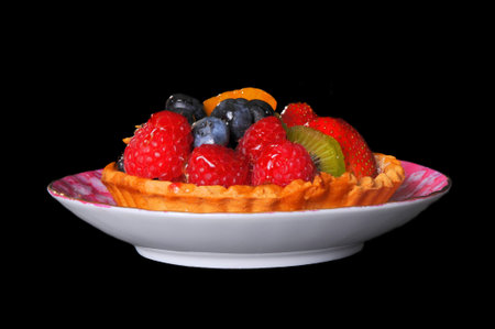 Fresh fruit tart isolated over black background
