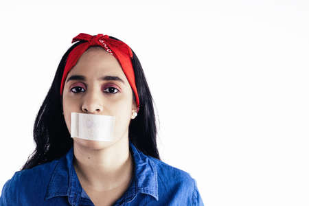 hispanic woman with tape on her mouth concept of feminism, on white background.の写真素材