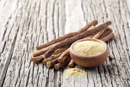 Licorice dry root with powder on wooden background