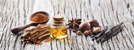 A bottle of essential oil with spices on wooden background. Cinnamon,vanilla, nutmeg and anise.の写真素材