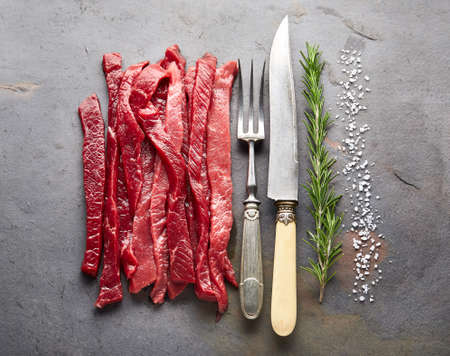 Beef stroganoff meat with rosemary on old black backgroundの写真素材