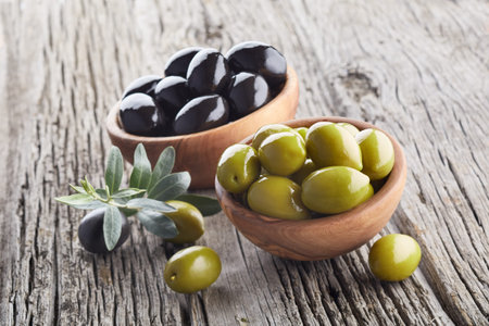 Black and green olives on wooden background