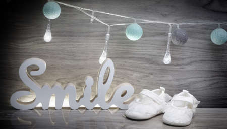 Blue cotton bals, little child's shoes and the word smile 3d on a wooden backgroundの写真素材
