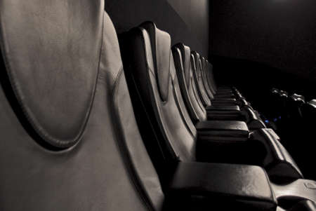 Empty black leather armchairs in the darkness of the cinema hall. Pandemic timeの写真素材