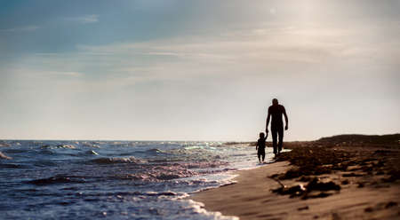 father and son to the sea at sunsetの写真素材