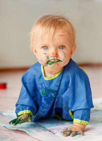 Little girl draws a colored paint sitting on the floorの写真素材