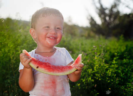 little baby eating watermelon outdoorsの写真素材