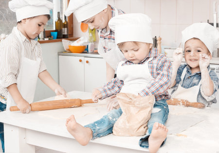 happy little chefs preparing dough in the kitchenの写真素材
