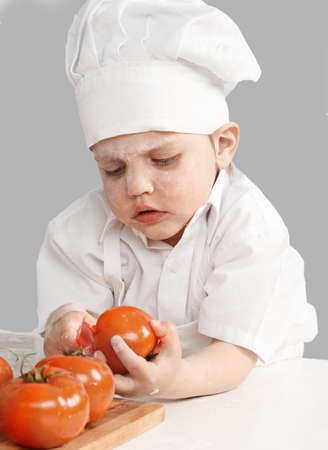 little boy chef cooking tomatoesの写真素材