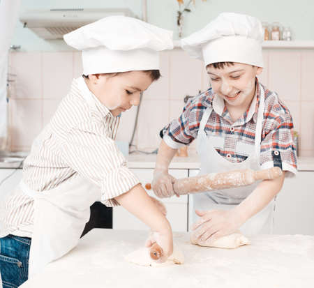 happy little chefs preparing dough in the kitchenの写真素材