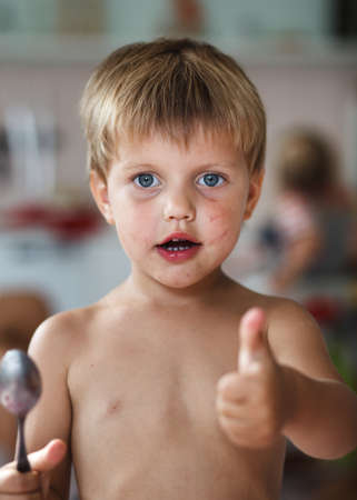 Little blonde boy holding a wooden spoonの写真素材