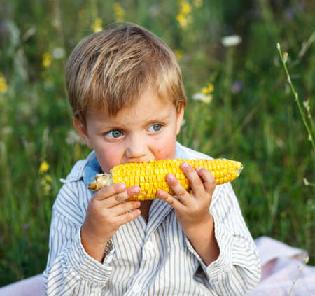 Adorable young boy eating corn on the cobの写真素材