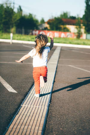 beautiful little girl runs down the road at sunsetの写真素材