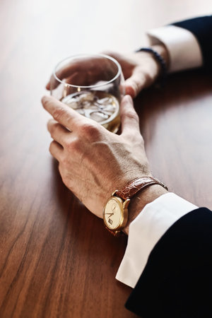 mans hand holding a glass of whiskey
