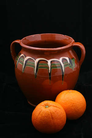 old ceramic pot and oranges on black backgroundの写真素材