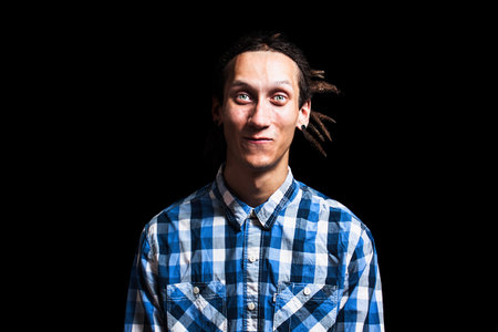 Portrait of a young cool man with dreadlocks on a black background