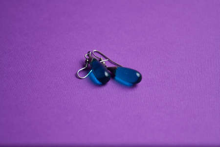 silver earrings with a blue stone on a purple backgroundの写真素材