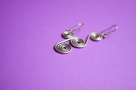 silver earrings in the form of a spiral on a purple backgroundの写真素材